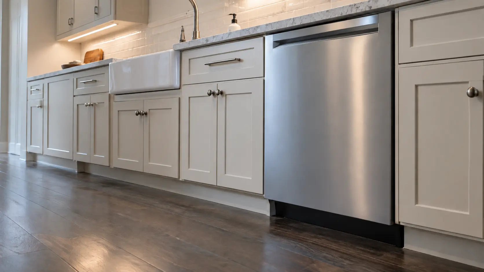 A dishwasher in a lakefront house kitchen in pale painted timber with a long run of units.