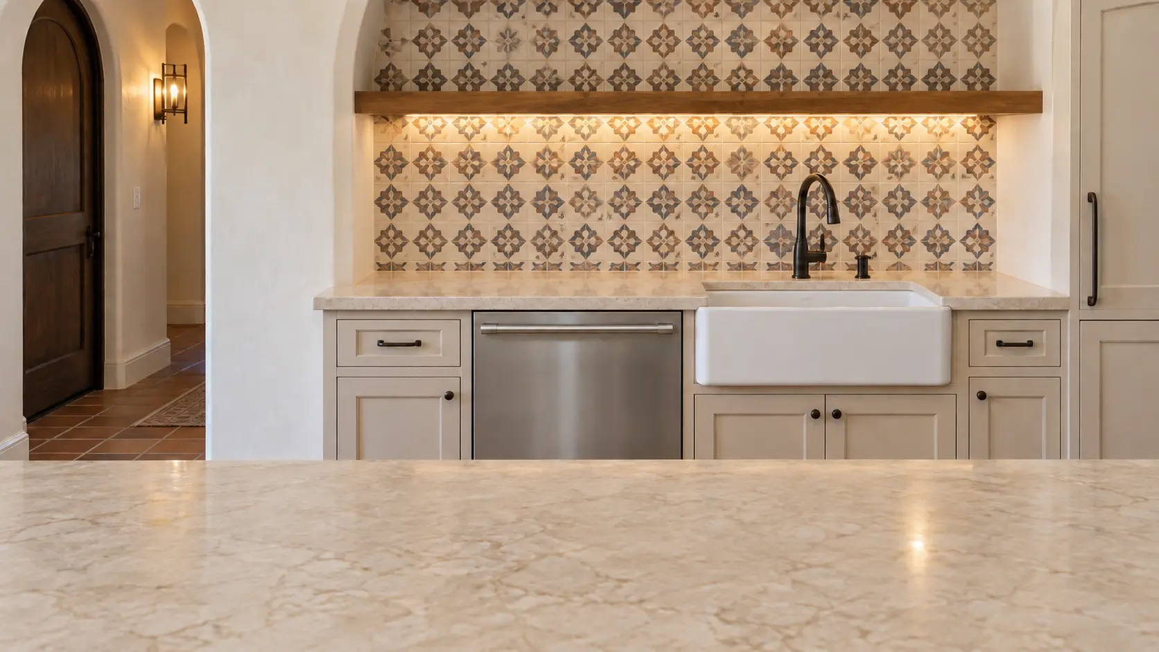 A dishwasher in a Spanish-revival kitchen with patterned tile and arched plaster.